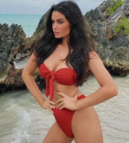 anne de paula is standing on the side of the beach